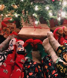 christmas presents under the tree with teddy bears and socks on them in front of a wrapped gift box