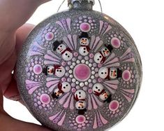 a hand holding a round ornament with snowmen on it's side