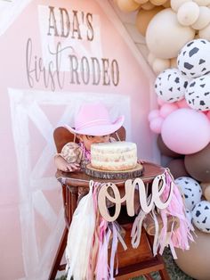 there is a cake and balloons on the table at this birthday party with pink, white and black decorations