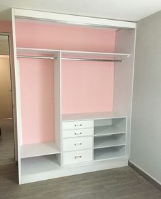 an empty closet with pink walls and white drawers