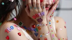 a woman with lots of colorful nail art on her body and hands, covering her face