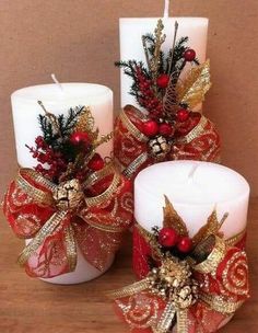 three white candles decorated with red and gold ribbons, pine cones and holly wreaths