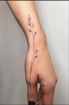 a woman's hand with a small flower tattoo on the left side of her arm