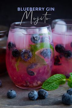 two glasses filled with blueberry gin mojito next to mint leaves and ice