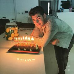 a man leaning over a cake with candles on it