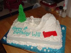 a birthday cake that is shaped like a snowman on a hill with trees in the background