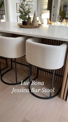 two white stools sitting at a counter in front of a dining room table and mirror