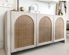 a white sideboard with wicker doors in a room