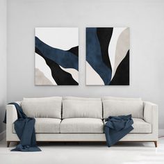 two paintings hang on the wall above a couch in a living room with white walls