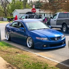 a blue car is parked on the side of the road in front of other cars