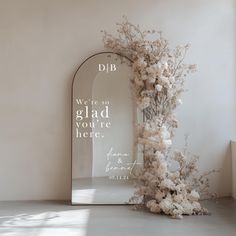 a mirror with flowers in front of it and a quote written on the back side