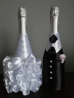 two black and white wine bottles are decorated with ribbons, bows and buttons on them