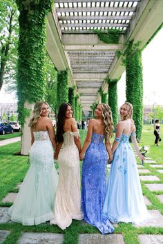 four beautiful women in dresses walking down the sidewalk together with their backs to each other