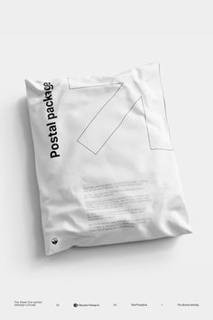 a white pillow sitting on top of a white floor next to a bag with black writing