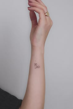 a woman's wrist tattoo with the letter n on her left hand and an arrow in the middle