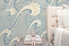 a bedroom with a bed, nightstand and wallpaper in blue waves on the walls