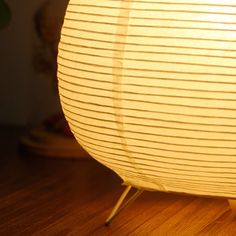 a close up of a lamp on a wooden floor with a blurry wall in the background