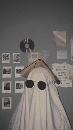 a white ghost wearing sunglasses and a hat with cd's on the wall behind it