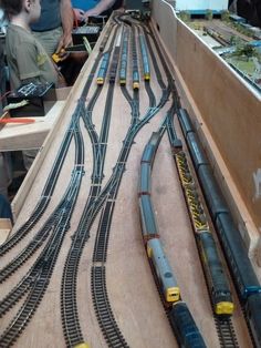 several children are playing with toy trains on the table and in front of them is a model train set