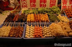 many different foods are being displayed on trays with chopsticks in front of them