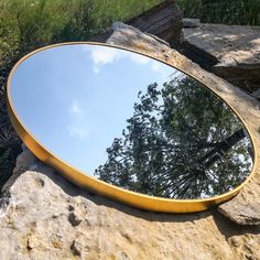 a round mirror sitting on top of a rock