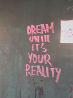 graffiti written on the side of a building reads dream until it's your reality