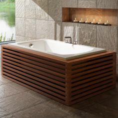 a bath tub sitting next to a window with candles on the ledges above it