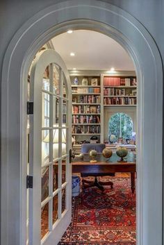 an arched doorway leads to a library with bookshelves and a table in the center