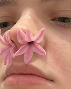 a close up of a person's nose with pink flowers on the tip of their nose