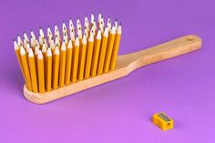 a wooden toothbrush with yellow and white bristles sitting on top of a purple surface