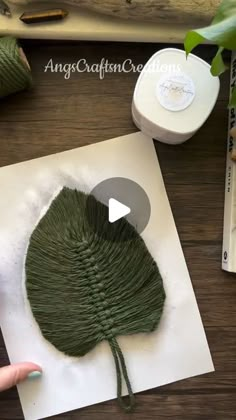 someone is making an art project out of yarn and paper with green leaves on it