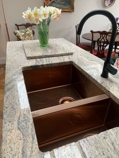 a kitchen sink with marble counter top and brown faucet