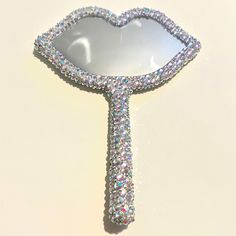 a mirror shaped like a heart with lots of crystals on the bottom and sides, sitting on a white surface