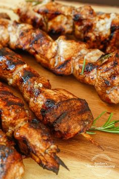 several skewers of meat on a wooden cutting board