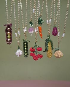 a bunch of necklaces hanging from chains with fruits and veggies on them