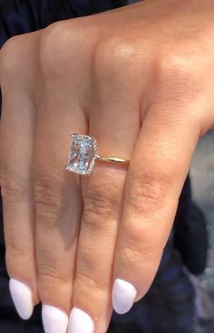 a close up of a person's hand with a diamond ring on their finger