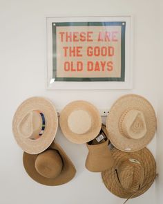 hats are hanging on the wall in front of a sign that says these are the good old days