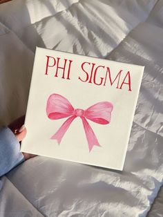 a person holding up a sign that says phi sigma with a pink bow on it