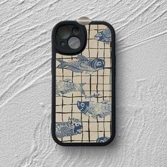 an iphone case with blue and white fish on the front, sitting on a wall