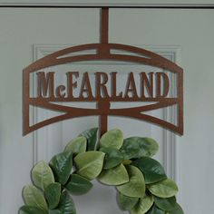 a wreath is hanging on the front door with a name sign above it that reads m & farland