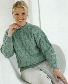 a woman sitting in a chair wearing a green sweater