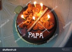 a chocolate birthday cake with lit candles on it