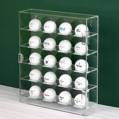 a display case with many golf balls in it on a table next to a green wall