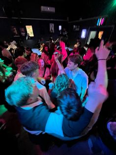 a group of people in a room with their arms around each other while one person holds his hand up