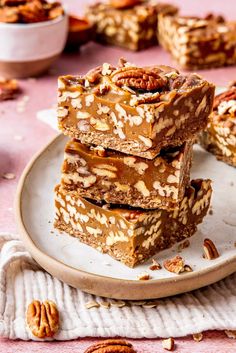 three pieces of pecan bar stacked on top of each other with nuts around them