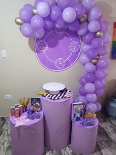 purple balloons and decorations are on display in front of a balloon arch at a birthday party