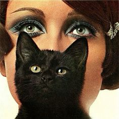 a woman is holding a black cat in front of her face and has it's eyes open