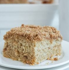 a close up of a piece of cake on a plate with a fork and bowl in the background