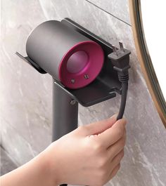 a person is holding the handle to a wall mounted light with a pink lens on it