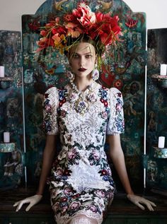 a woman with flowers on her head sitting on a bench